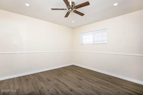 an empty room with a ceiling fan and wooden floor
