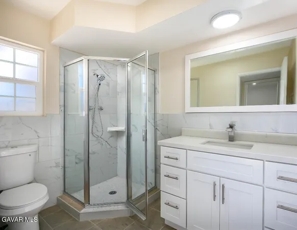 a bathroom with a shower sink vanity mirror and toilet