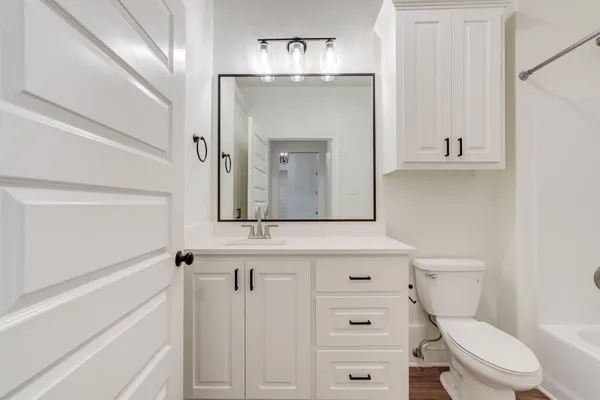 a bathroom with a granite countertop toilet sink and mirror