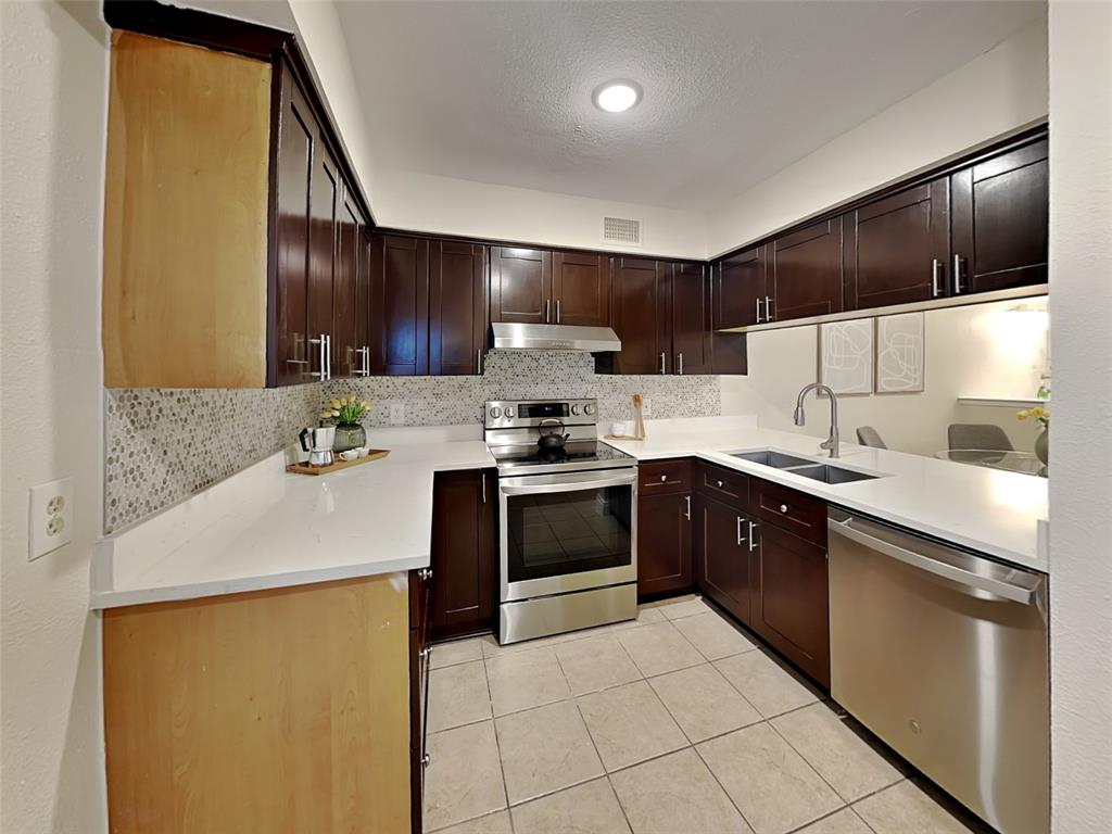 4220 Madera Road Irving, TX 75038 - Photo 11 of 22 Kitchen featuring under cabinet range hood, visible vents, a sink, light tile patterned flooring, and appliances with stainless steel finishes