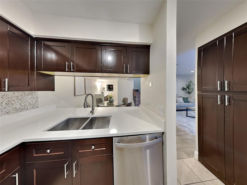 4220 Madera Road Irving, TX 75038 - Photo 10 of 22 Kitchen with stainless steel dishwasher, a sink, dark brown cabinetry, backsplash, and light countertops