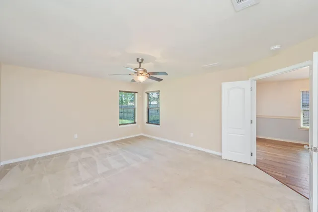 an empty room with windows and chandelier fan
