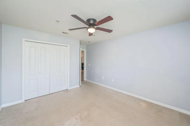 an empty room with windows and fan