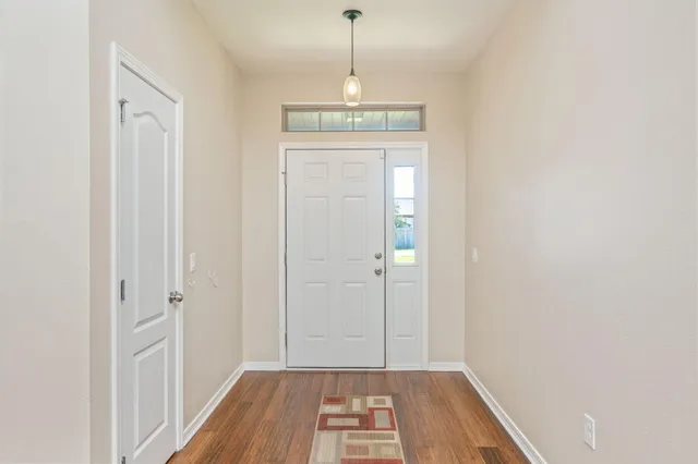 a view of a hallway with wooden floor and a chandelier