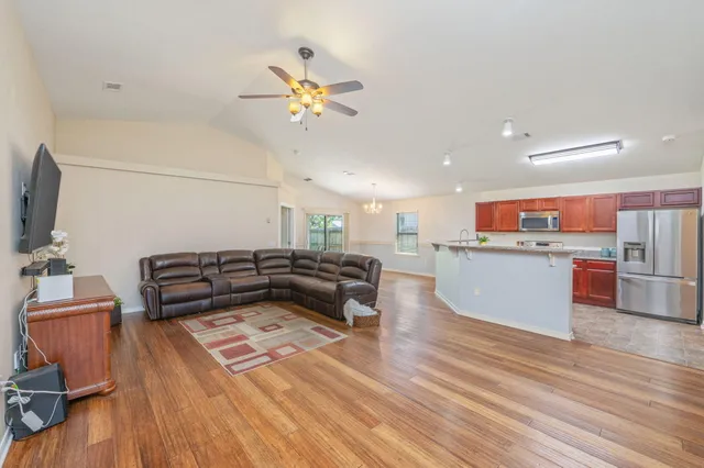a living room with stainless steel appliances furniture and a kitchen view