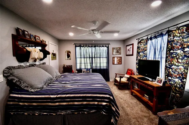 a bedroom with a bed a flat screen tv and guitar