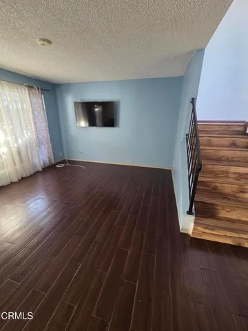 a view of an empty room with wooden floor and stairs