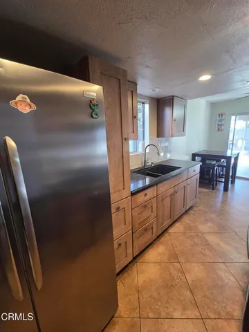 a kitchen with stainless steel appliances granite countertop a refrigerator a sink a stove and a refrigerator