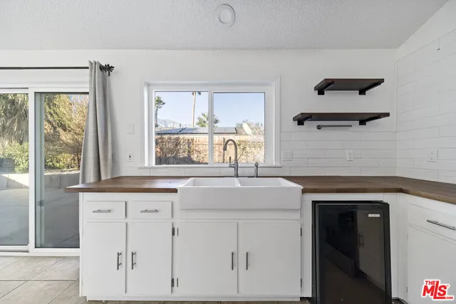a kitchen with white cabinets and window
