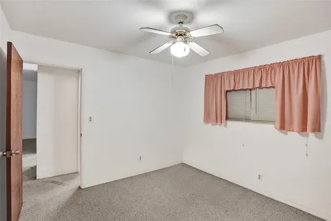 an empty room with a ceiling fan and a window