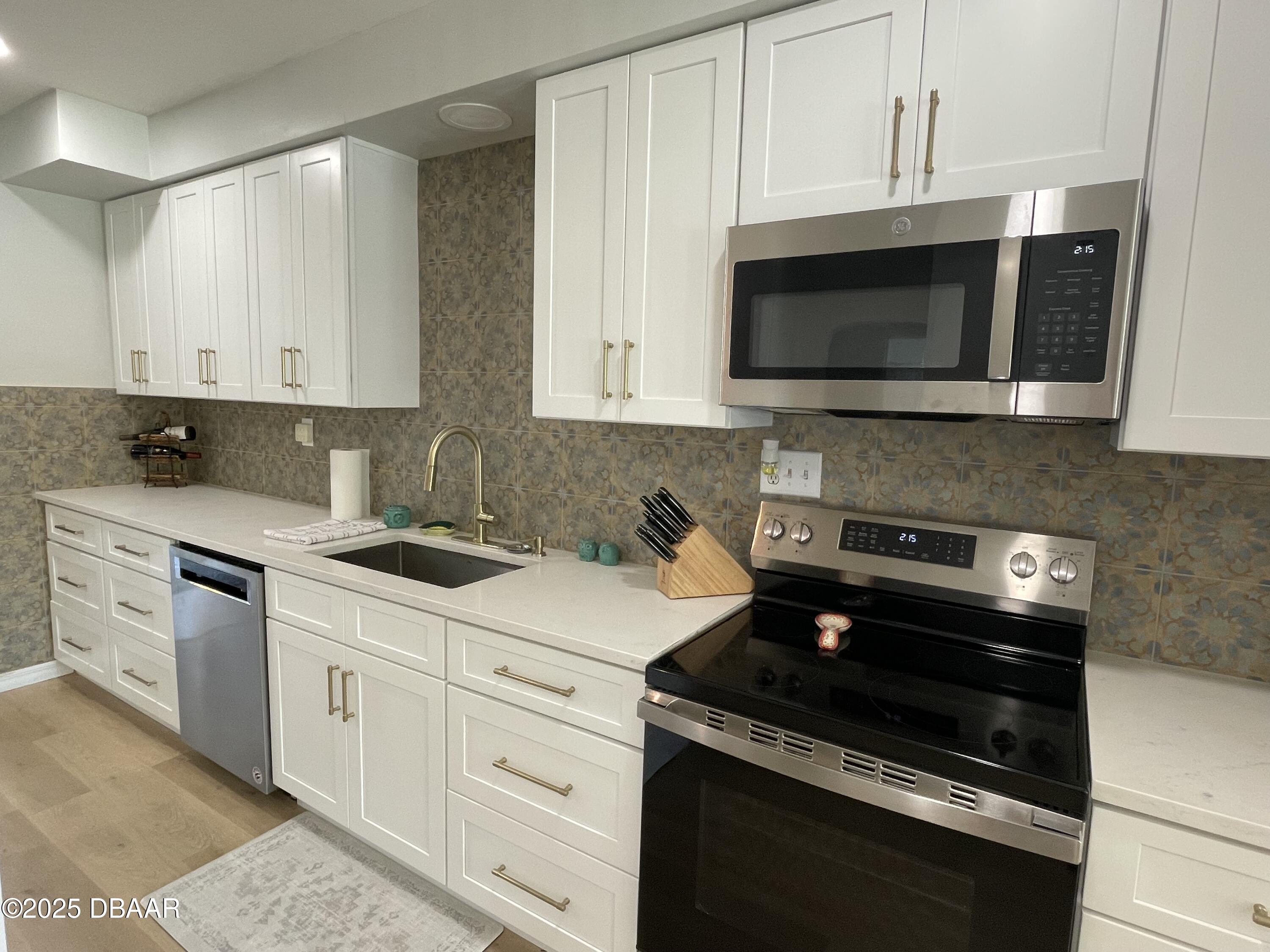 43 Warwick Avenue Ormond Beach, FL 32174 - Photo 7 of 32 a kitchen with stainless steel appliances granite countertop white cabinets a stove top oven and a sink