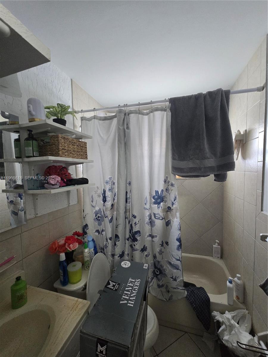 5709 Lincoln Street Hollywood, FL 33021 - Photo 6 of 17 a bathroom with a bathtub a sink and a shower curtain