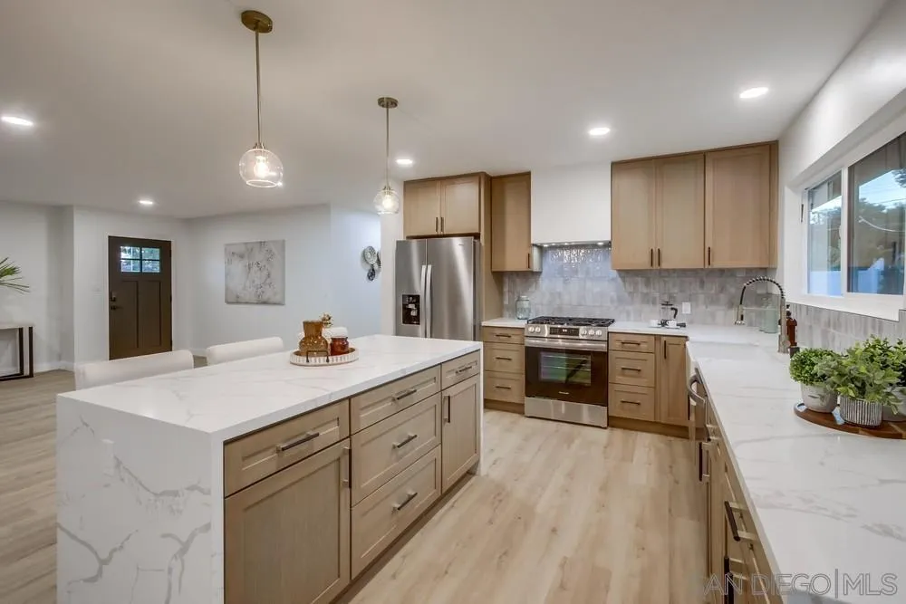12378 Wade Way El Cajon, CA 92021 - Photo 20 of 48 a kitchen with stainless steel appliances kitchen island granite countertop a stove a sink a refrigerator and a oven with wooden floor