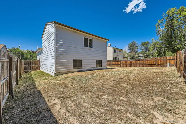 a backyard of a house with plants and wooden fence