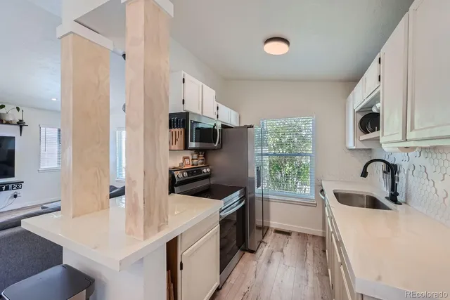 a kitchen with stainless steel appliances a sink a stove a microwave a sink a refrigerator and cabinets