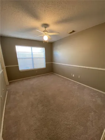 an empty room with windows and fan