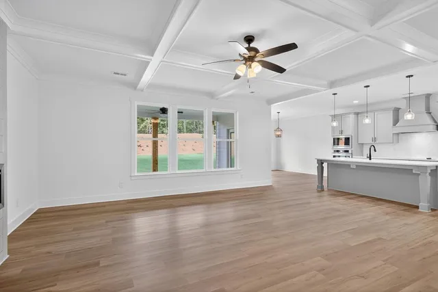 a kitchen with stainless steel appliances granite countertop a sink a refrigerator a center island a stove and a wooden floor