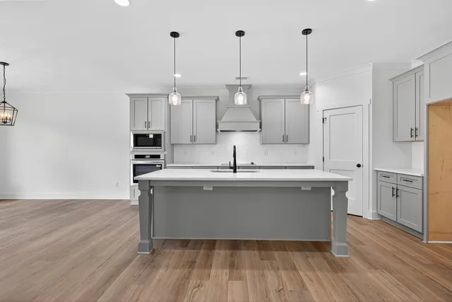 a kitchen with stainless steel appliances granite countertop a sink a stove a refrigerator and a island with wooden floor