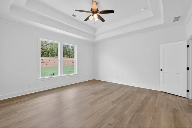 a view of an empty room with wooden floor and bathroom