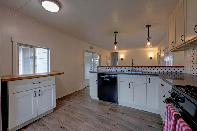 a kitchen with granite countertop a stove a sink and a wooden floors