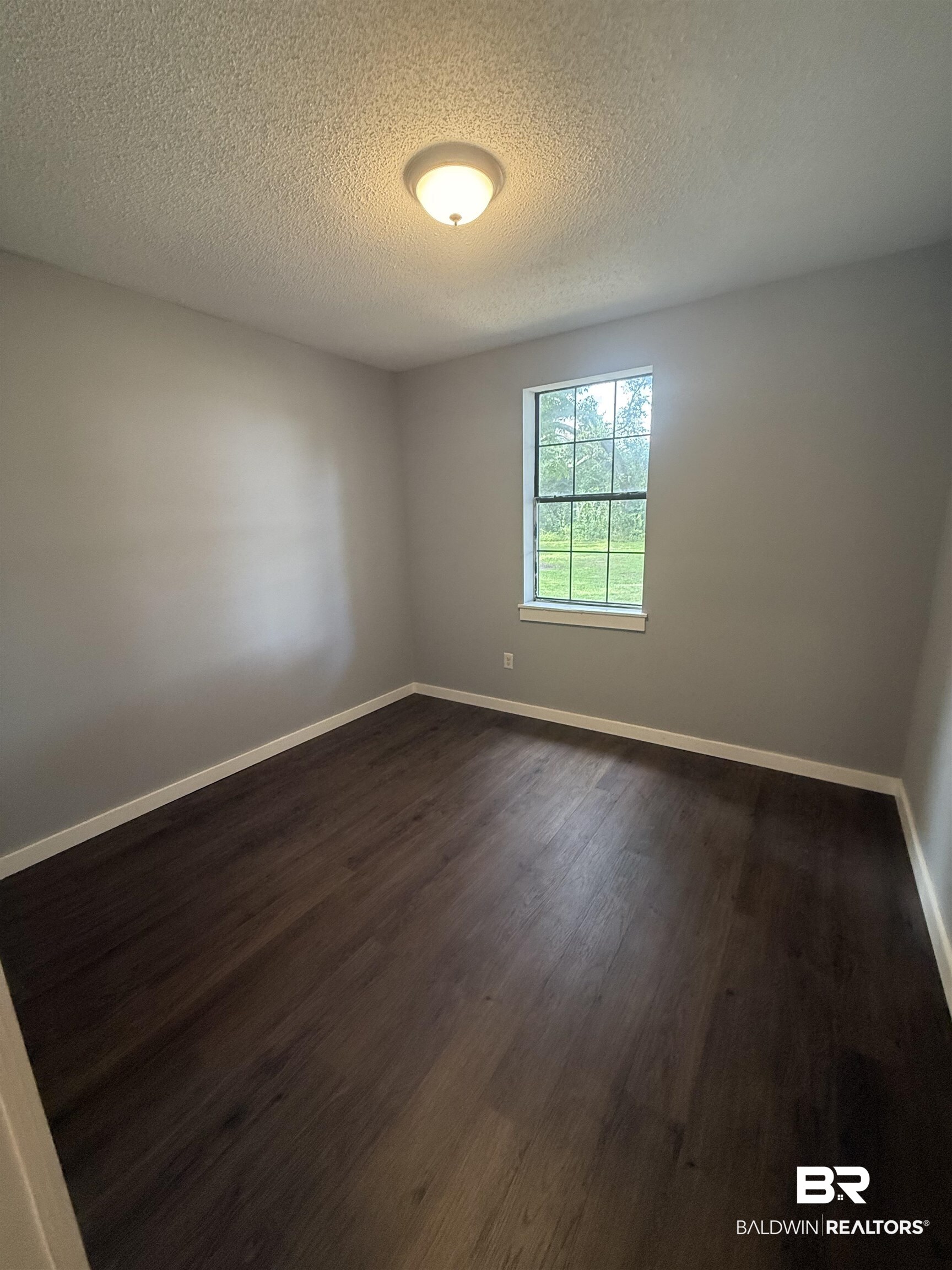 17440 Old Brady Road Bay Minette, AL 36507 - Photo 8 of 9 Unfurnished room featuring dark wood-type flooring and a textured ceiling