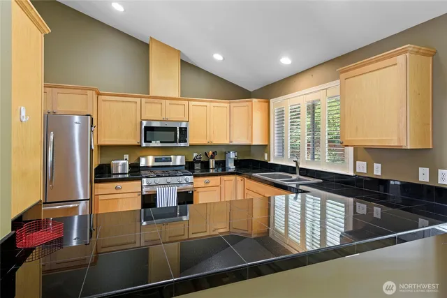 a kitchen with stainless steel appliances granite countertop a sink a stove and a refrigerator