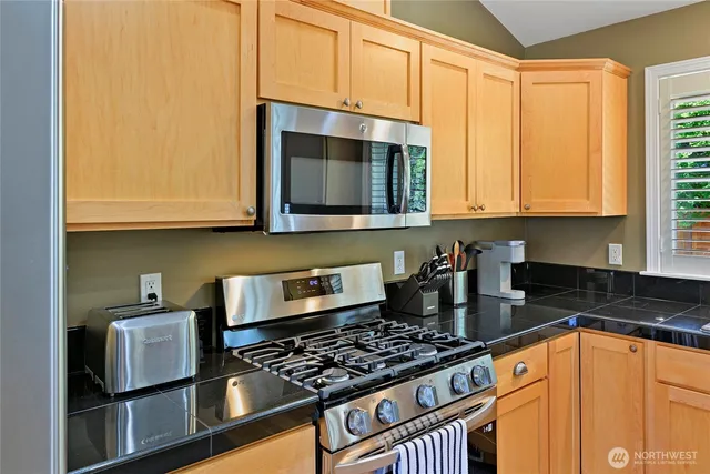 a kitchen with granite countertop a stove a sink and a microwave