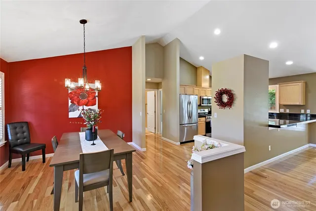 a kitchen with stainless steel appliances kitchen island granite countertop a dining table chairs and a refrigerator
