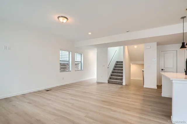 an empty room with wooden floor and stairs