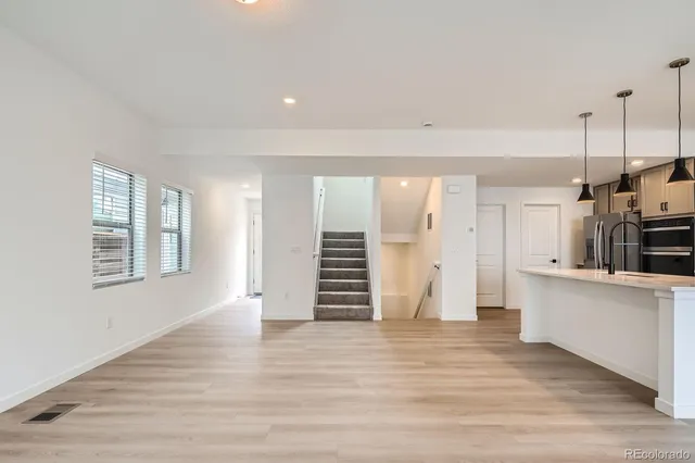 a view of kitchen and empty room with wooden floor and window