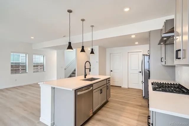 a large kitchen with stainless steel appliances kitchen island a large counter top and a wooden floors