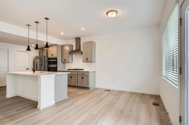 a kitchen with stainless steel appliances kitchen island granite countertop a refrigerator a sink a stove and white cabinets with wooden floor