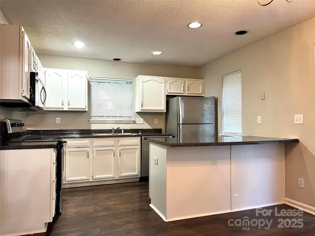 a kitchen with stainless steel appliances granite countertop a stove a sink and a refrigerator with wooden floor