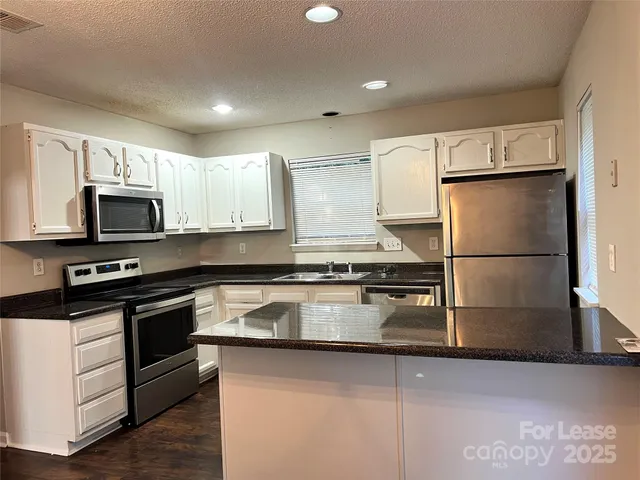 a kitchen with granite countertop a refrigerator stove and microwave