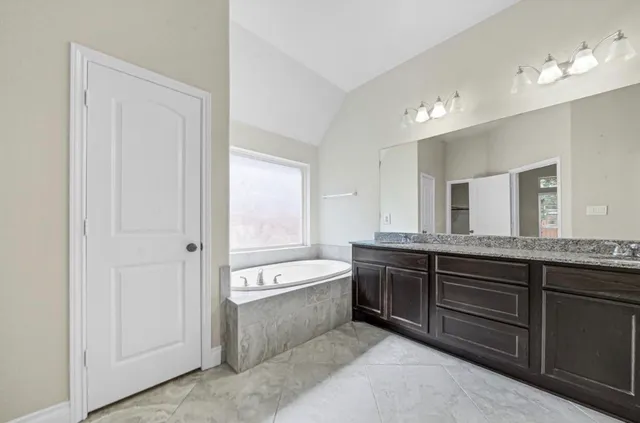 a spacious bathroom with a tub sink and mirror