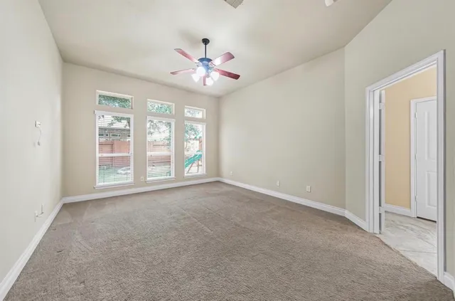 an empty room with chandelier fan and windows