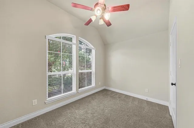 an empty room with windows and fan