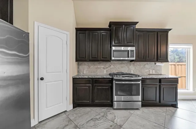 a kitchen with stainless steel appliances granite countertop wooden cabinets and a stove top oven
