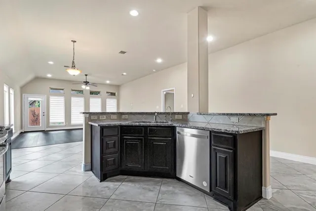 a kitchen with kitchen island granite countertop a stove and a sink