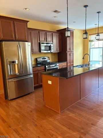 a kitchen with stainless steel appliances granite countertop a refrigerator a sink a stove a microwave and island