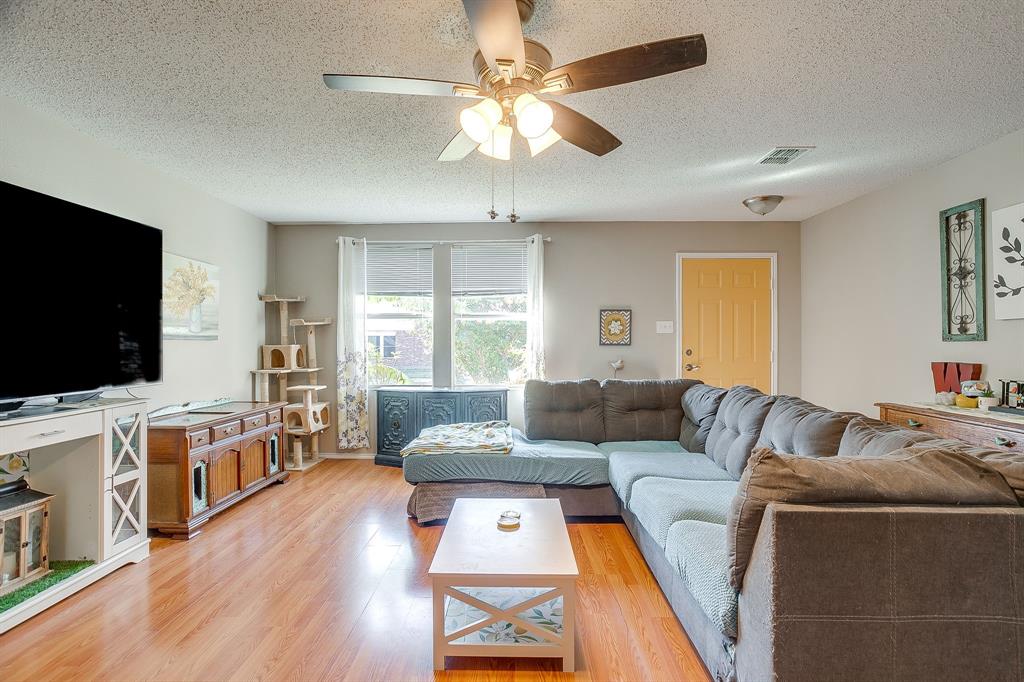 Living area featuring wood-finish flooring, a ceiling fan with light fixture, and neutral wall paint