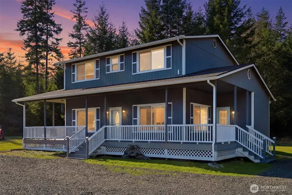 a view of a house with a yard and deck area under a large tree
