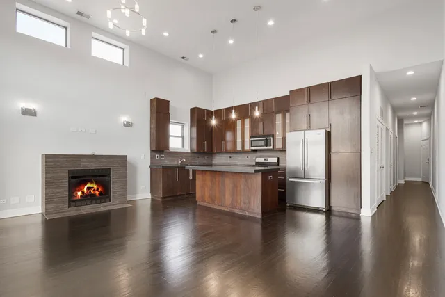 a kitchen with stainless steel appliances a refrigerator a stove top oven a fireplace and wooden floor