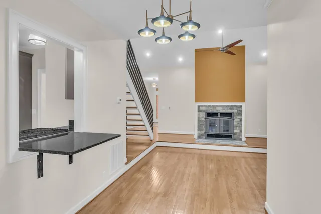 a view of an empty room with chandelier fan and wooden floor
