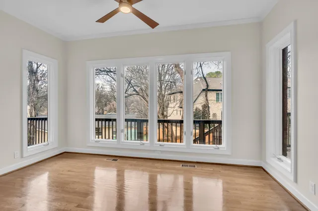 a view of an empty room with a window and wooden floor