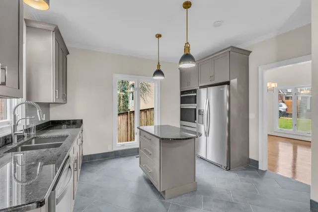 a kitchen that has a refrigerator a stove a sink and a dining table with chairs