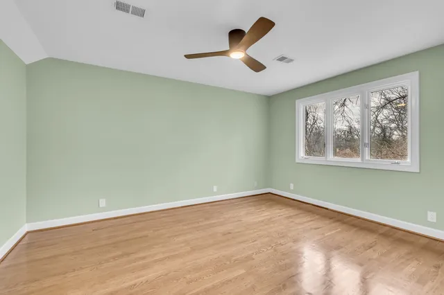 a view of a room with wooden floor a ceiling fan and window