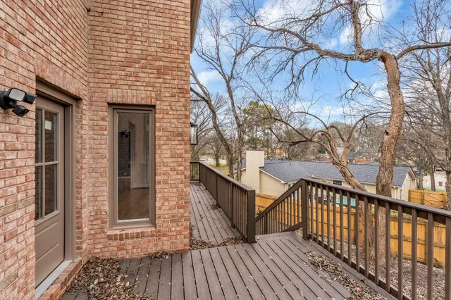 a view of balcony with wooden floor and fence and a trees