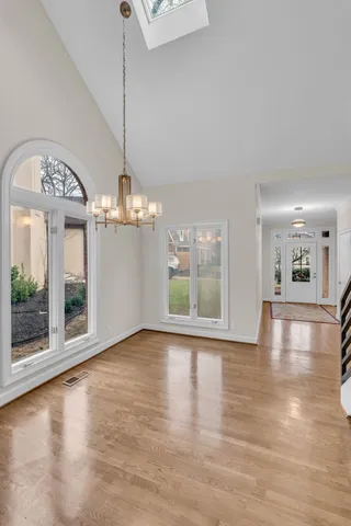 a view of a room with wooden floor chandelier and windows