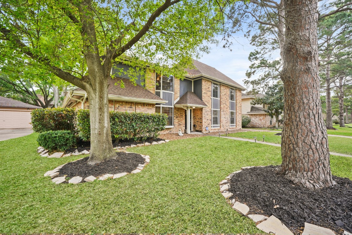 15831 Ridge Park Drive Houston, TX 77095 - Photo 21 of 26 This charming two-story brick home features large windows, a well-maintained lawn, and mature trees. The landscaping includes neatly trimmed bushes and stone-bordered flower beds, creating an inviting curb appeal.